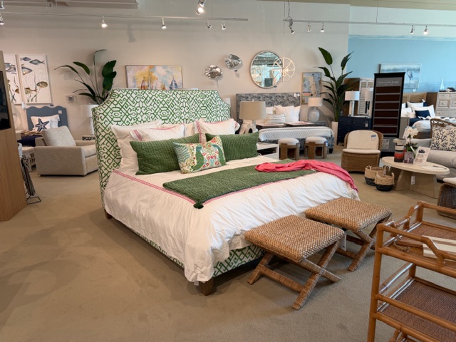 Green bedframe and white linens with two stools at end of bed