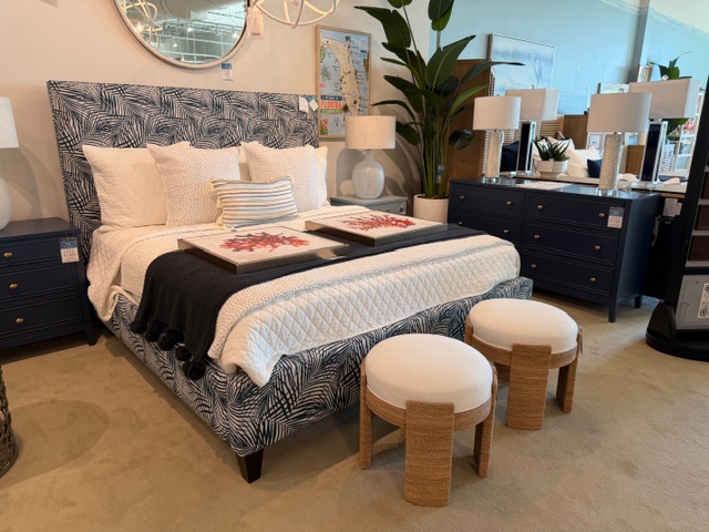 Blue upholstered bed wuth dark blue throw and bolce stools at end of bed